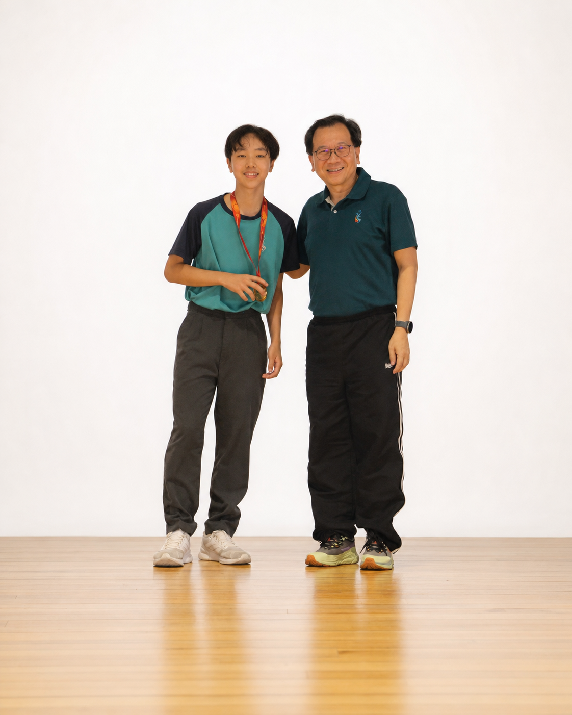 boy with gold medal stands on stage with principal